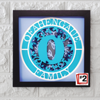 Framed artwork with a blue circle design and text on a textured white wall.