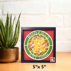 Framed decorative item with 'ROBERTS' and '1986' on a table with a plant in the background