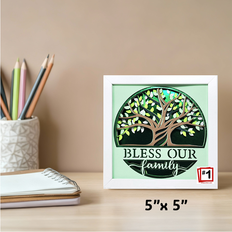 Framed artwork with a tree design and 'Bless Our Family' text on a desk.
