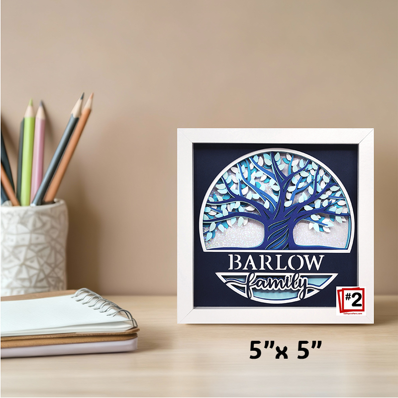 Framed artwork with a tree design and 'Barlow Family' text on a desk with stationery items.