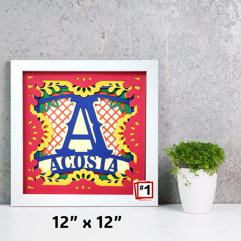 Framed colorful artwork with letter 'A' and text on a gray wall with a plant.