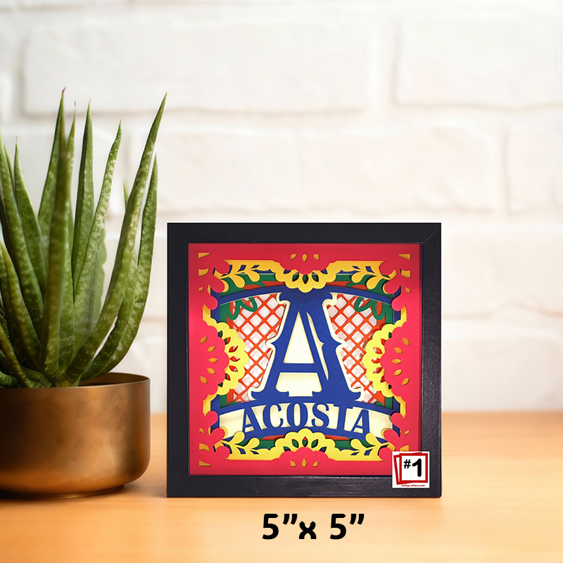 Framed artwork with colorful design and text, placed on a surface next to a plant.