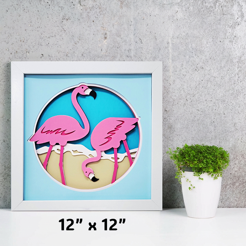 Framed artwork of pink flamingos on a beach with a plant in the background