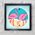 Framed artwork of two pink flamingos on a beach with a blue sky.
