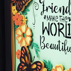 Decorative sign with flowers and butterflies and text 'Friends make the world beautiful' on a light green background.