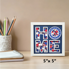 Decorative wall art with 'HOME' text in a frame on a desk with stationery items.