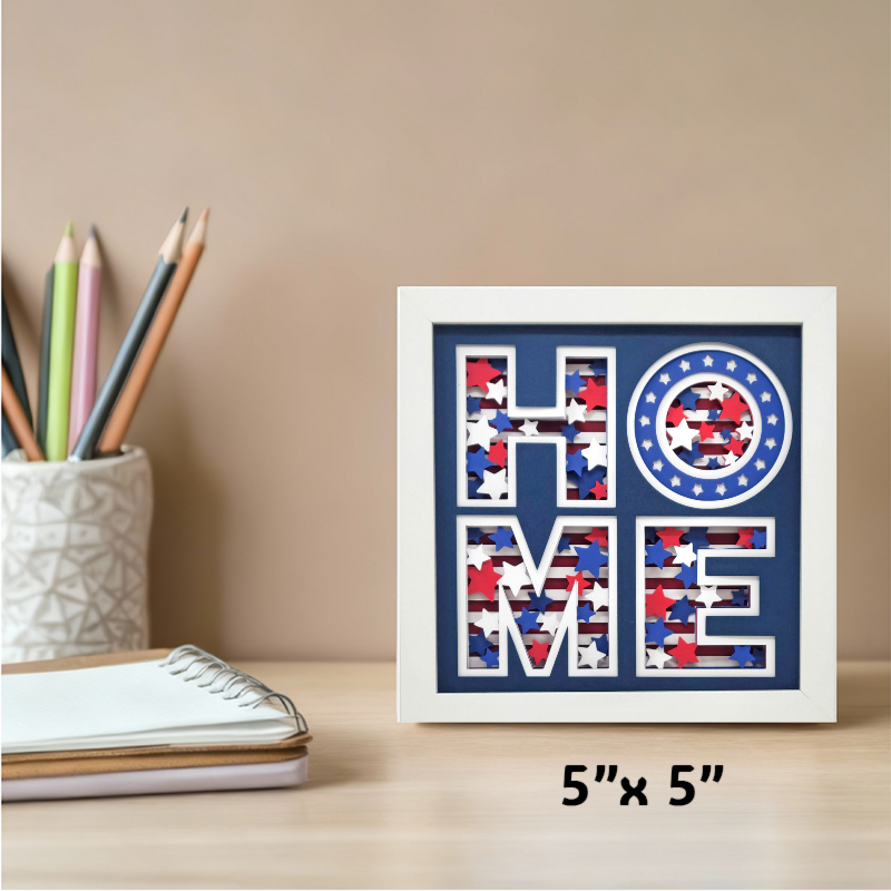 Decorative wall art with 'HOME' text in a frame on a desk with stationery items.