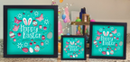 Three 'Happy Easter' framed pictures on a decorative surface with Easter decorations in the background.