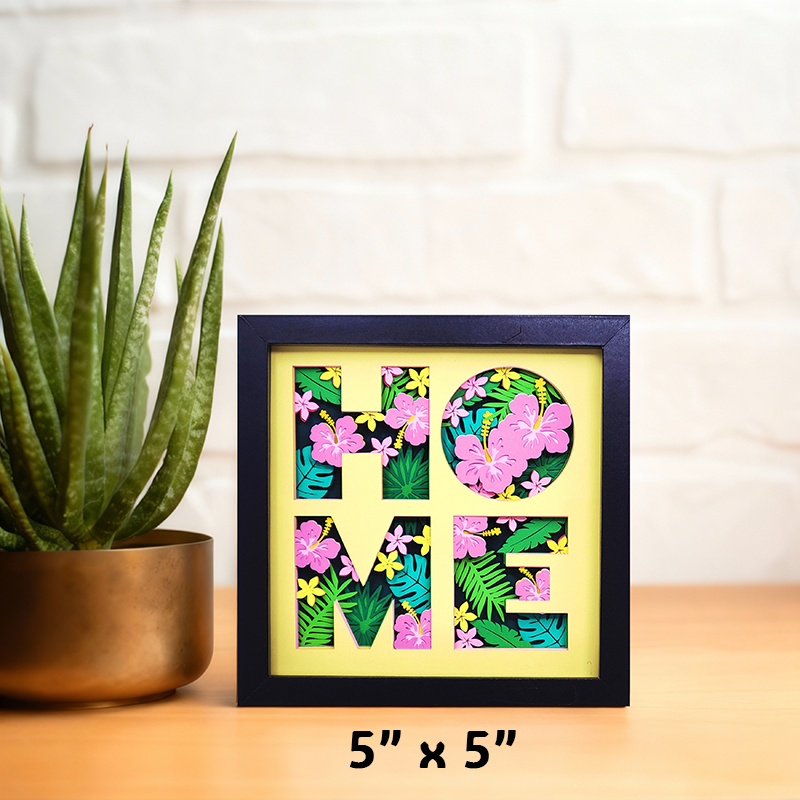 Decorative wall art with 'HOME' letters made of flowers on a wooden surface with a plant.