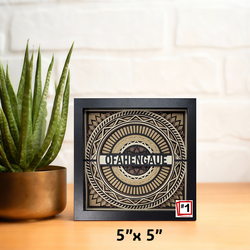 Decorative wall art with geometric design and 'OFAHENGAUE' text on a wooden surface with a plant.
