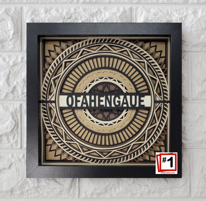 Decorative wall art with geometric design and 'OFAHENGAU' text on a textured white wall.