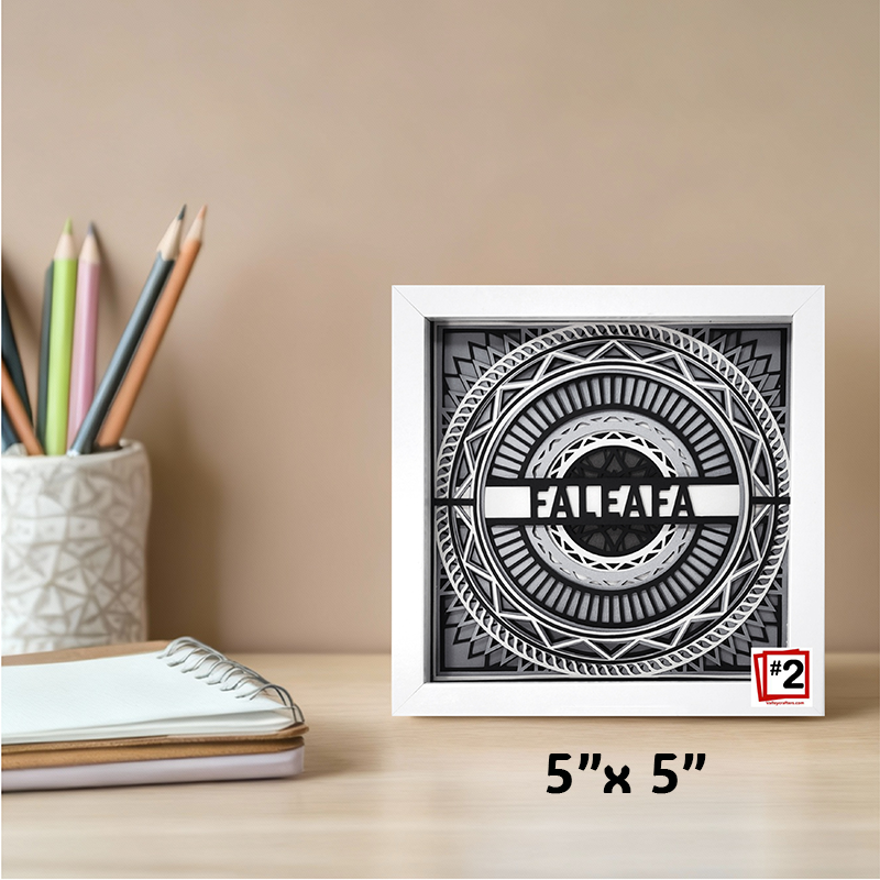 Framed black and white artwork with 'FALEAFA' on a desk with stationery items.