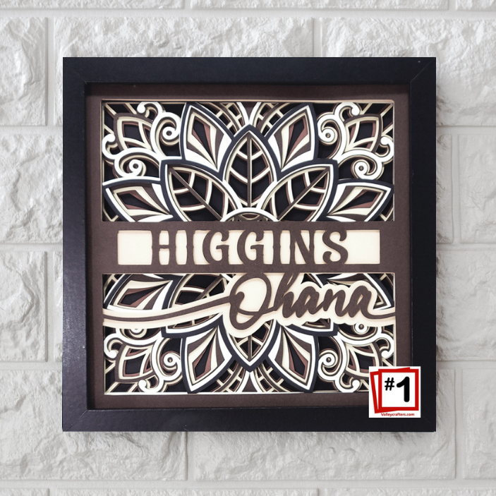 Decorative wall art with 'Higgins Ohana' text in a black frame on a textured white wall.