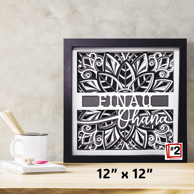 Framed decorative wall art with floral design and text on a wooden surface.