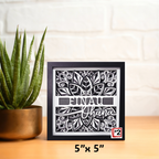 Framed decorative art piece with 'Finau Ohana' text and plant on a wooden surface