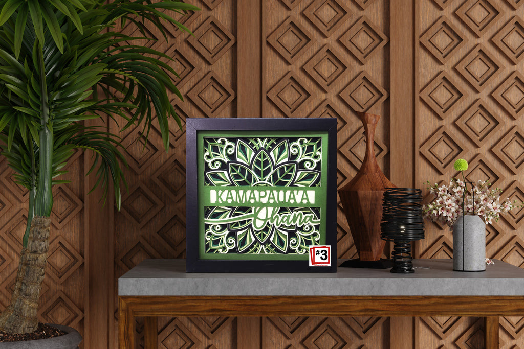 Decorative framed artwork with text on a table against a wooden wall.