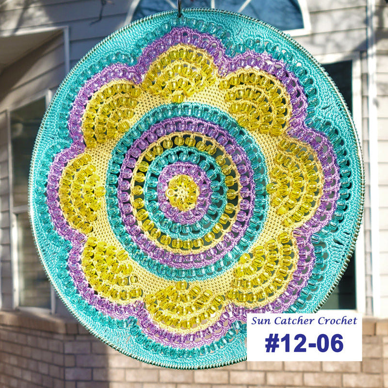 Colorful crochet sun catcher with 'Sun Catcher Crochet' label and number #12-06 in front of a house.