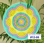 Colorful crocheted sun catcher with a plant in the background