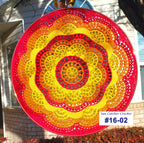 Circular sun catcher with colorful pattern in front of a house