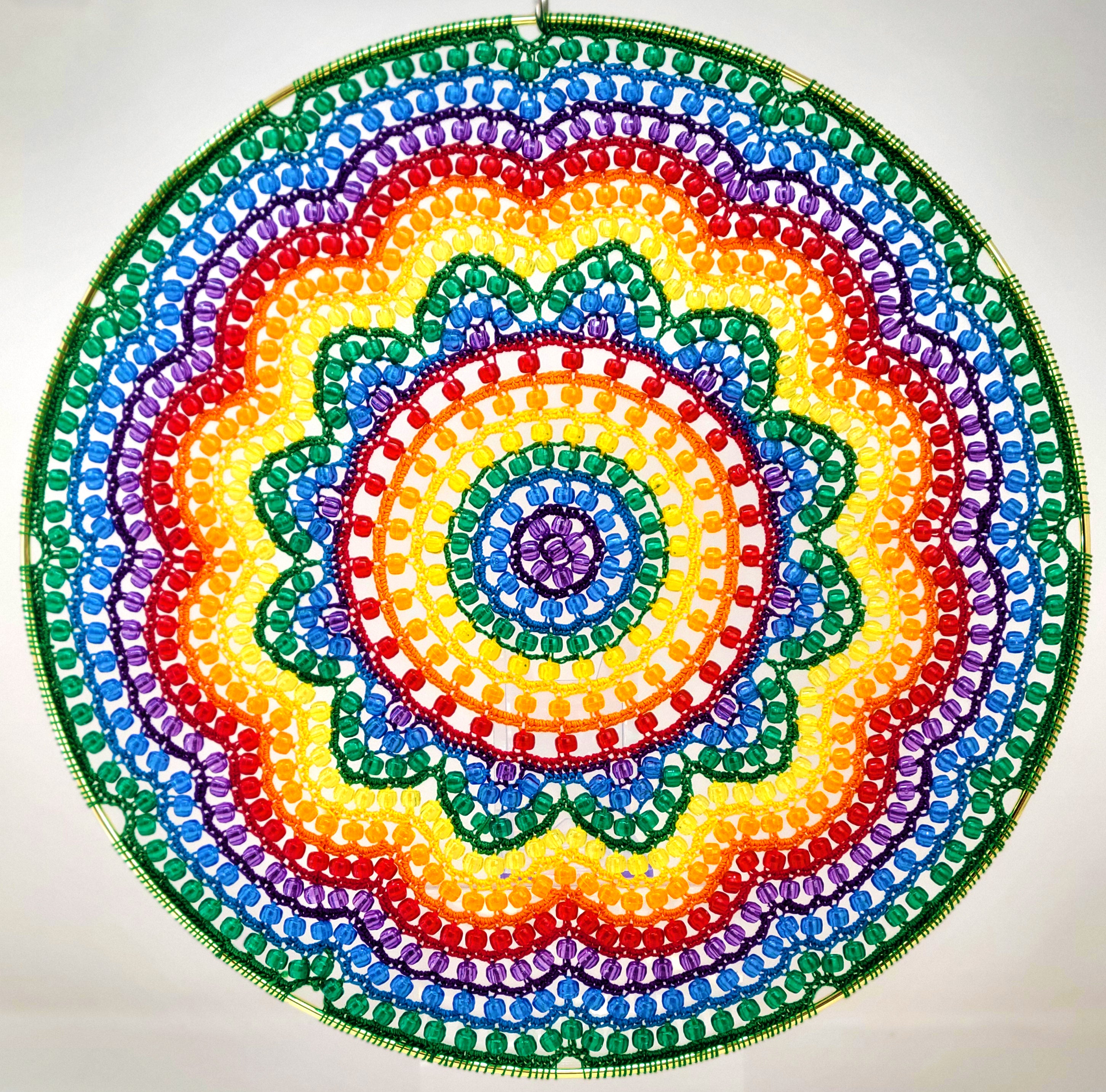 Colorful beaded mandala with a rainbow pattern on a white background
