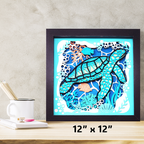 Framed artwork of a turtle and underwater scene on a wooden surface with a mug and books.