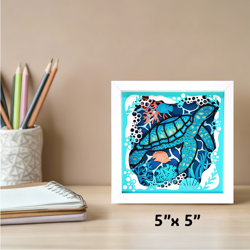 Framed artwork of a blue fish with coral on a beige surface with stationery items.