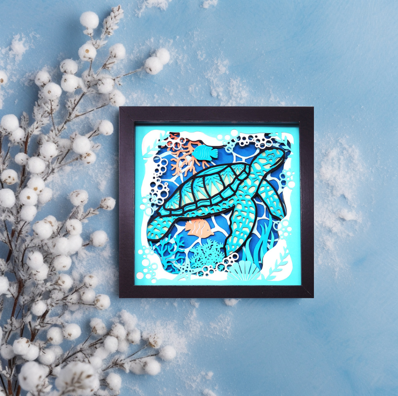 Framed artwork of a turtle with coral on a blue background with white decorative elements.