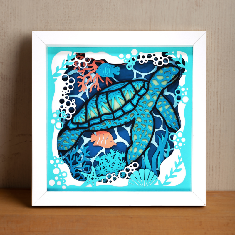 Framed artwork of a stylized turtle with ocean-themed design on a wooden surface.