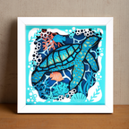 Framed artwork of a stylized turtle with ocean-themed design on a wooden surface.