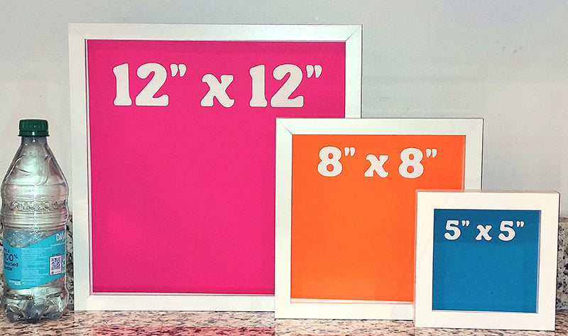 Three picture frames with different sizes displayed next to a bottle.