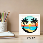 Framed artwork of a tropical sunset with palm trees on a desk with stationery items.