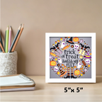 Framed Halloween-themed artwork on a desk with stationery items.