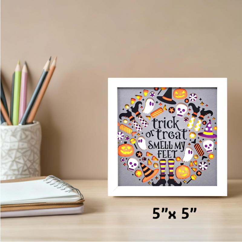 Framed Halloween-themed artwork on a desk with stationery items.