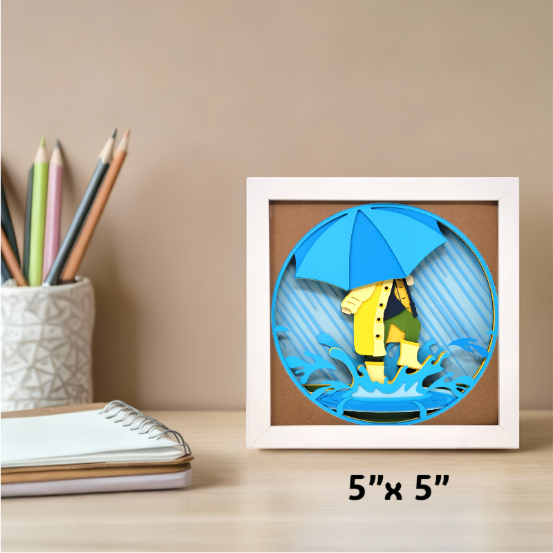 Framed artwork of a person with a blue umbrella on a desk with stationery items.