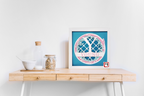 Framed artwork on a wooden desk with a white wall background