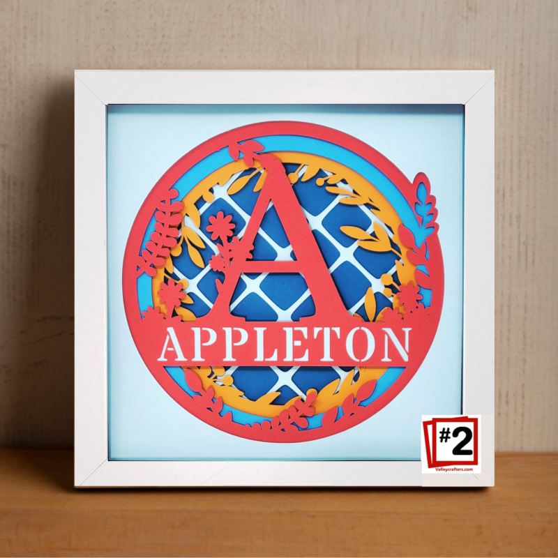 Framed artwork with colorful letter 'A' and 'APPLETON' text on a light blue background.