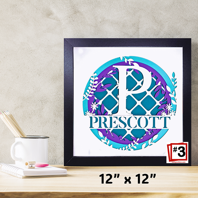 Framed decorative wall art with a monogram and name on a desk.