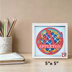 Framed decorative item with 'APPLETON' text on a desk with stationery items.
