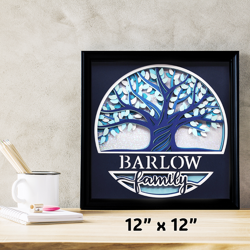 Framed artwork of a tree with 'Barlow Family' text on a wooden surface.