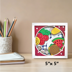 Framed artwork of food items on a desk with stationery