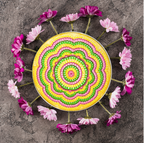 Colorful circular design with pink flowers arranged around it on a gray surface