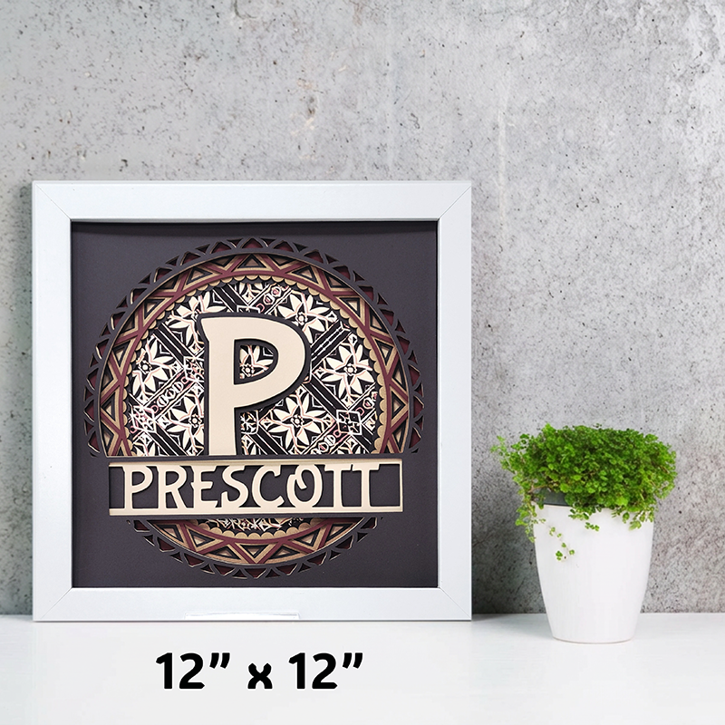 Decorative wall art with a letter 'P' and name 'Prescott' in a white frame on a gray wall.