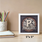 Decorative wall art with a letter 'P' and name 'Prescott' on a wooden surface with stationery items.