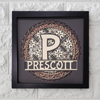 Decorative wall art with a stylized 'P' and 'Prescott' text in a black frame on a textured white wall.