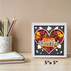 Framed decorative sign with pumpkin and leaves design on a desk with stationery items.