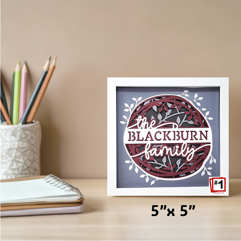 Framed artwork with 'the Blackburn family' text on a desk with stationery items.