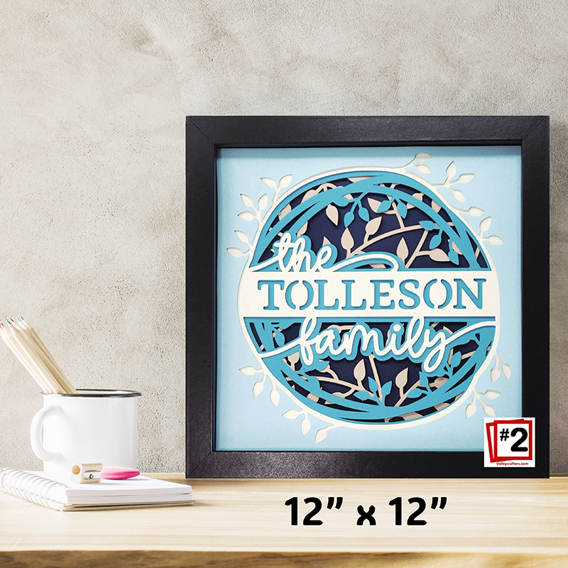 Framed artwork with 'the TOLLESON family' text on a light blue background, displayed on a desk.