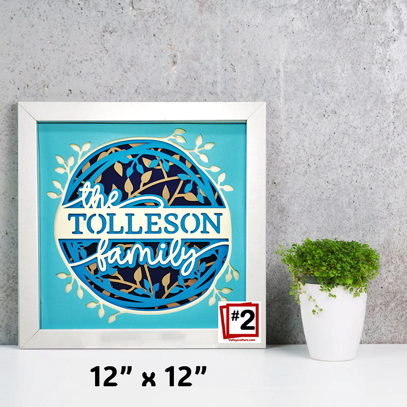 Framed artwork with 'The Tolleson Family' text on a blue background, next to a potted plant.