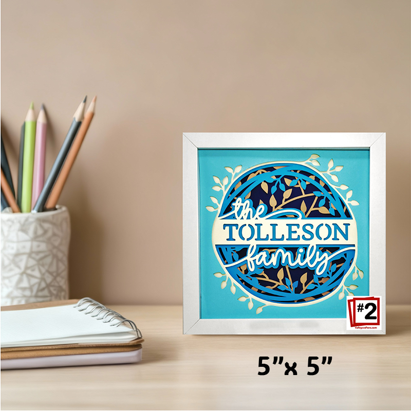 Framed artwork with 'the Tolleson family' on a desk with stationery items.