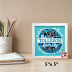 Framed artwork with 'the Tolleson family' on a desk with stationery items.